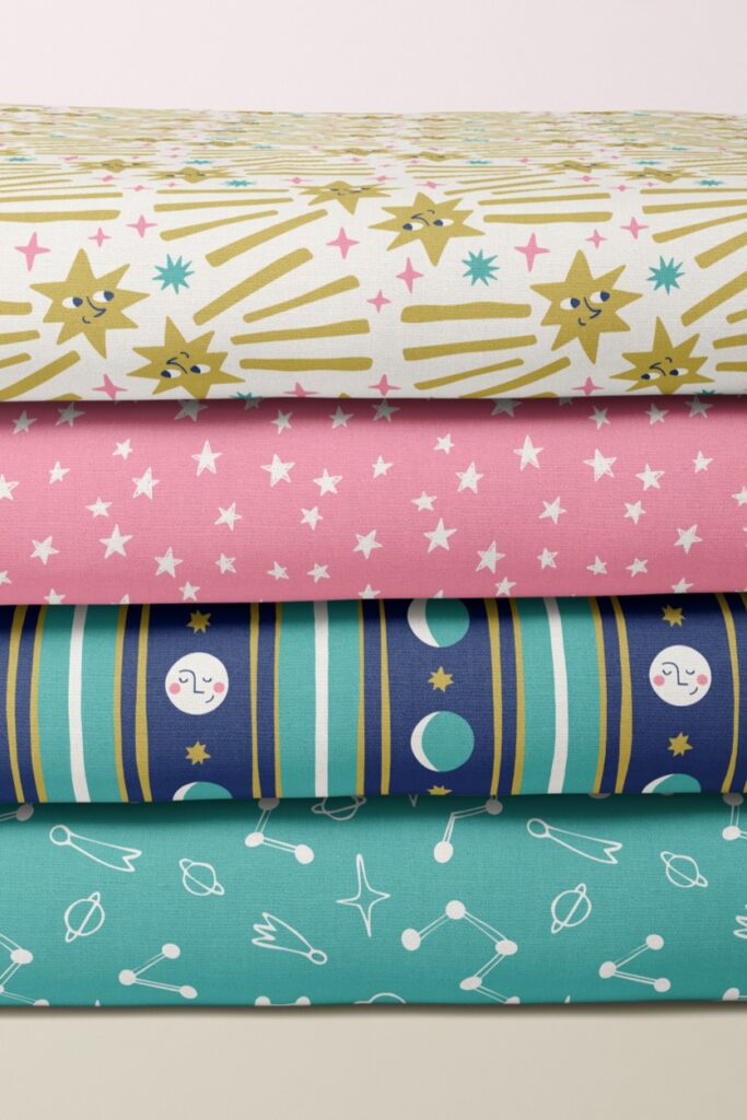 celestial fabrics for kids' clothing, featuring fun space motifs such as smiling shooting stars and playful moon phases, in a bold yellow, teal and pink palette